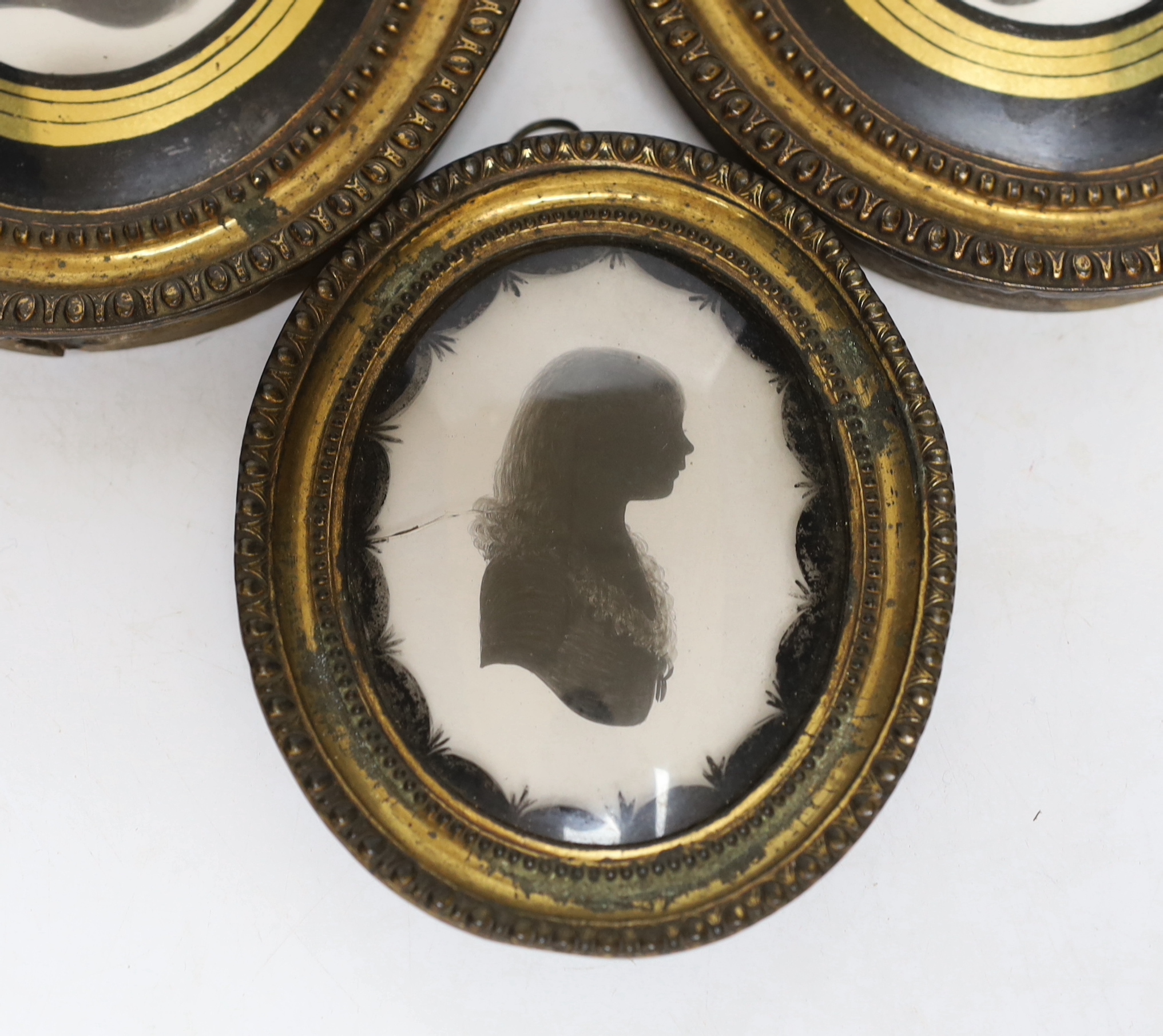 Three late Georgian silhouette portraits, verre eglomise mounts, largest 17cm high